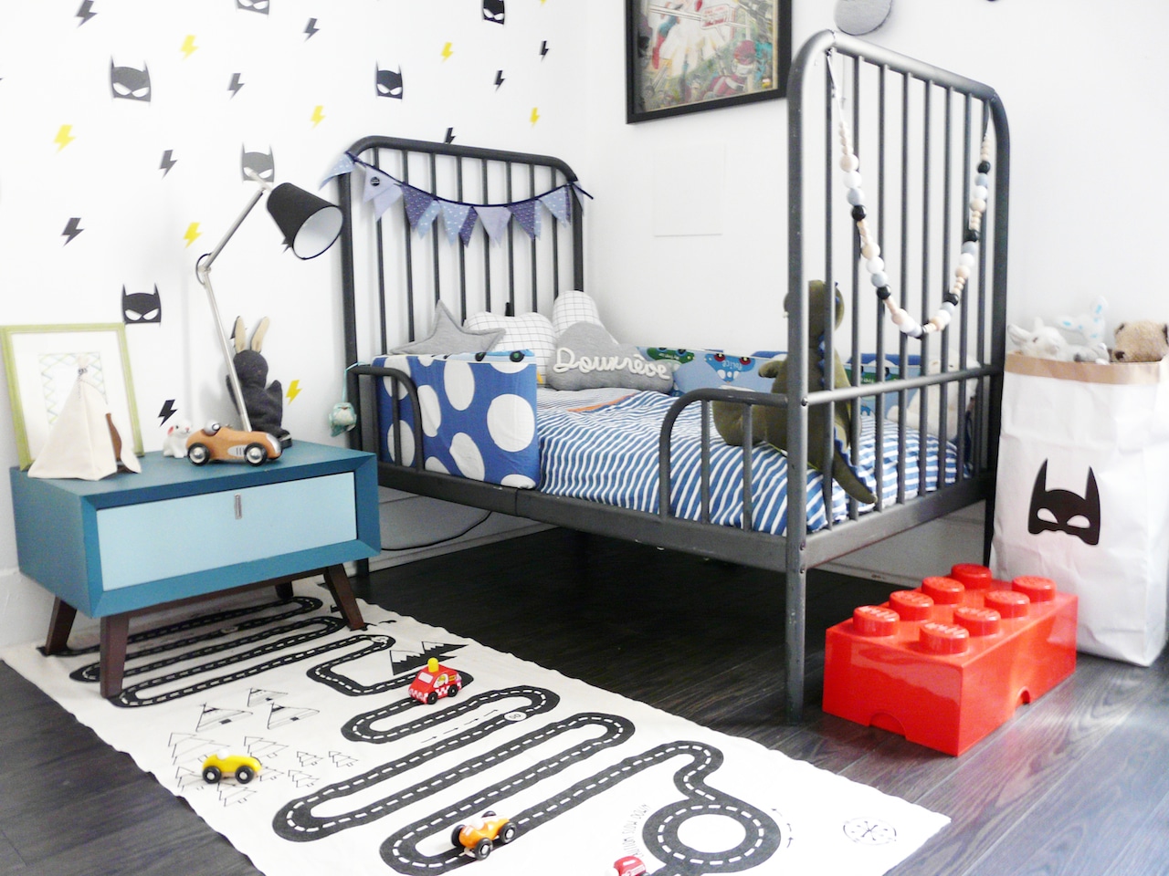 Chambre d'enfant décorée sur le thème Superhéros avec un tapis piste de course de voiture, des stickers muraux et un mot en tricotin