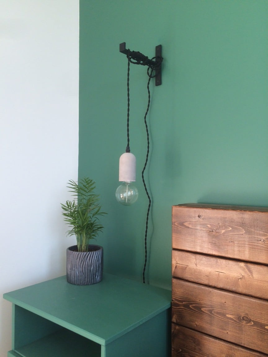 chambre verte avec équerre et luminaire suspendu à une équerre en fonte