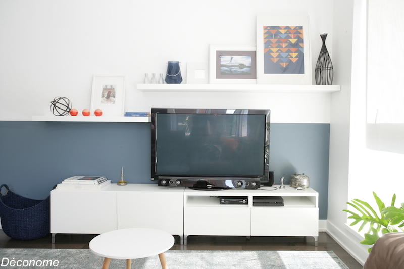 étagère avec cadres superposés sur un demi-mur peint en bleu