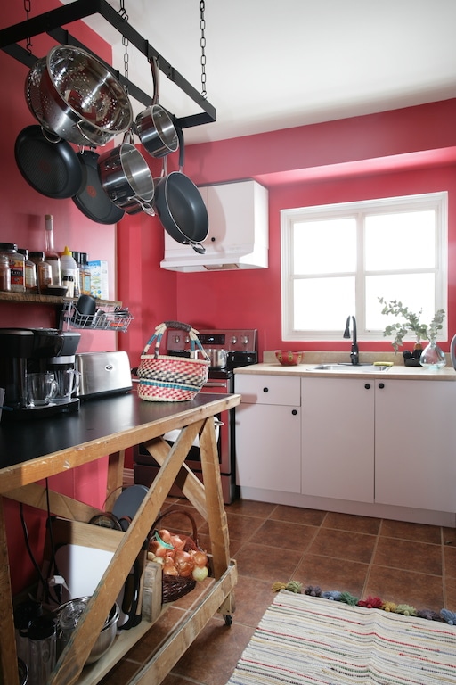 établi en bois et crémaillère à chaudrons / Red kitchen with wooden table and hanging pot rack