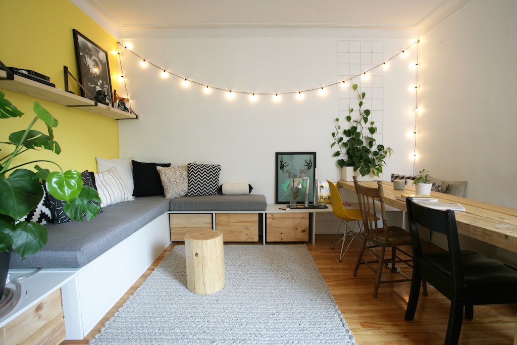 Banquette et table fabriquée sur mesure. Guirlande lumineuse au mur / Living room with a homemade sofa bench and wood plank table 