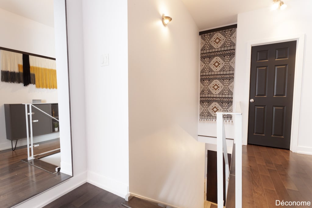 Décoration de couloir avec tapis suspendu dans la cage d'escalier et miroir agrandissant